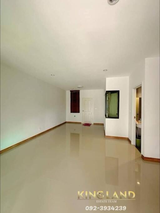 Spacious empty living room with glossy tiled floors and a doorway to additional rooms