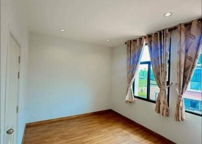 Spacious bedroom with wooden floor and natural light