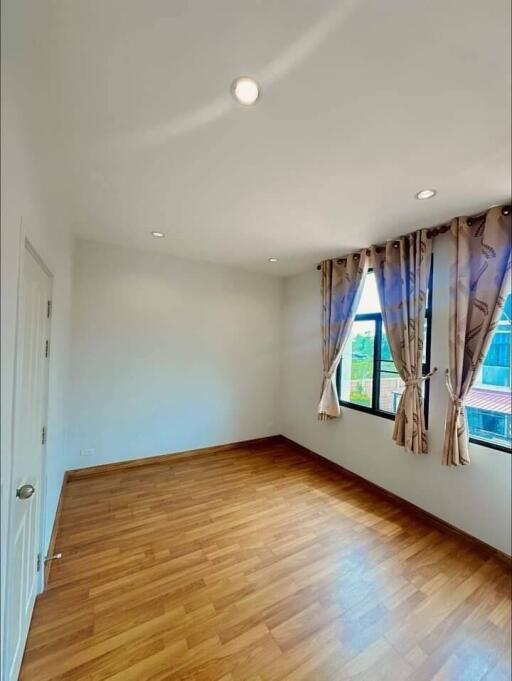 Spacious bedroom with wooden floor and natural light