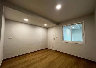 Minimalist bedroom with wooden flooring, a window, and a white door