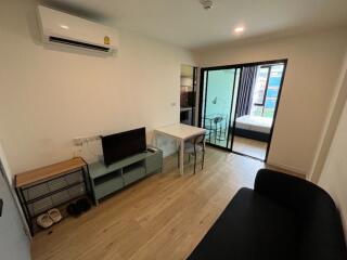 Modern living area with a TV, small table, and adjoining bedroom