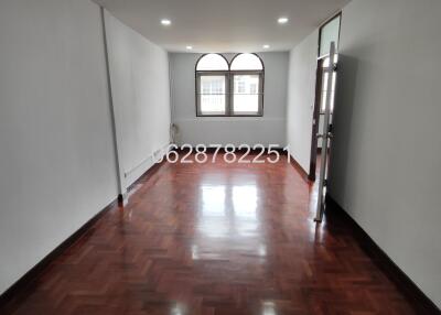 Spacious, empty living room with wooden floor and large window