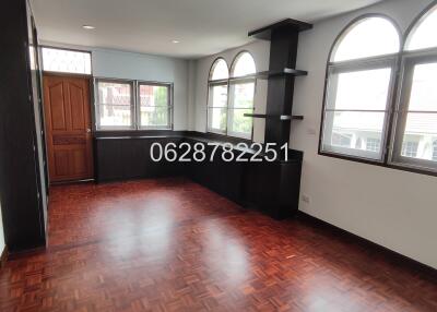 Empty living room with wooden floor, large windows, and built-in shelving