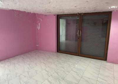 Empty room with pink walls, tiled floor, and sliding glass door