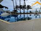 Outdoor swimming pool area with palm trees and ocean view