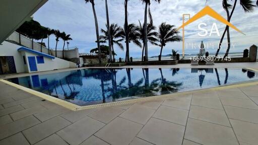 Outdoor swimming pool area with palm trees and ocean view