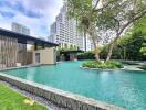 Modern residential swimming pool surrounded by greenery and buildings