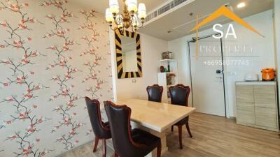 Dining area with a floral feature wall and a chandelier