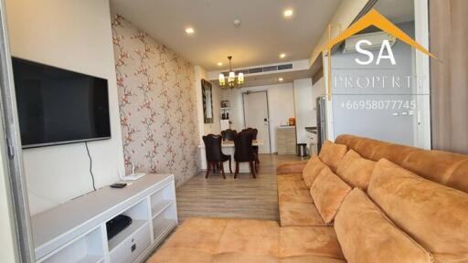 Living room with TV, brown sectional sofa, and dining area