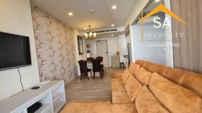 Living room with a brown sofa, wall-mounted TV, and adjacent dining area