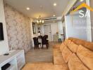 Living room with a brown sofa, wall-mounted TV, and adjacent dining area