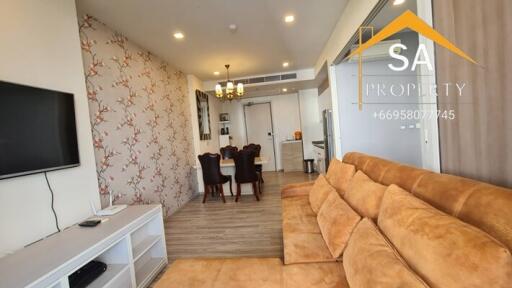 Living room with a brown sofa, wall-mounted TV, and adjacent dining area