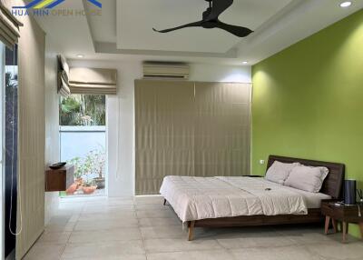 Modern bedroom with green accent wall and ceiling fan