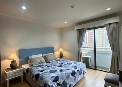 Spacious bedroom with a large bed, wooden flooring, and balcony access