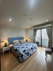 Spacious bedroom with a large bed, wooden flooring, and balcony access