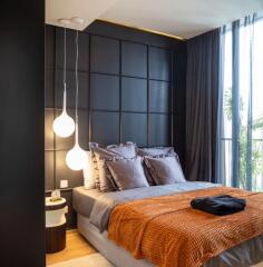 Modern bedroom with a large bed, dark paneled wall, pendant lights, and floor-to-ceiling windows.