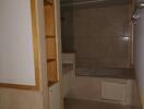 A bathroom with beige tiles, a bathtub, built-in shelves, and a dual camera photo notice.