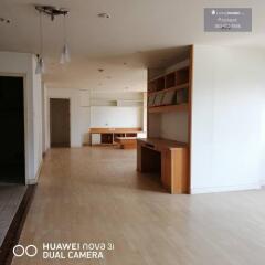 Spacious living area with wooden flooring and built-in shelves