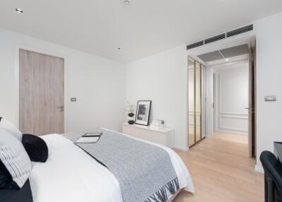 Modern, spacious bedroom with light wood flooring, built-in closet, and minimalist decor