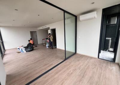 Unfurnished living room with glass partition and people packing belongings