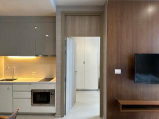 Modern kitchen with overhead cabinets, built-in microwave, and living area with mounted TV