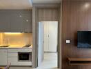 Modern kitchen with overhead cabinets, built-in microwave, and living area with mounted TV