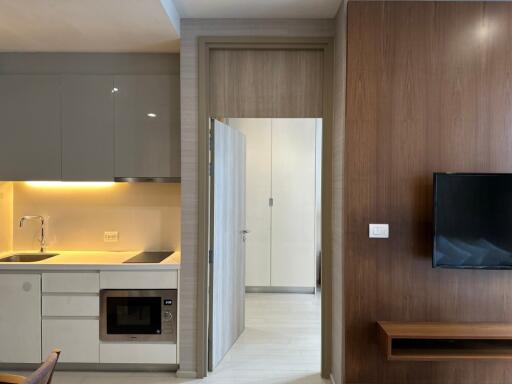 Modern kitchen with overhead cabinets, built-in microwave, and living area with mounted TV