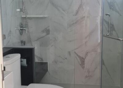 Modern bathroom with glass shower enclosure and marble walls