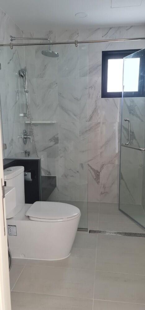 Modern bathroom with glass shower enclosure and marble walls