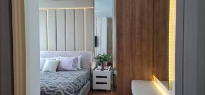 Modern bedroom with stylish decor featuring a bed, bedside table, wooden accent wall, and indoor plants