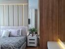 Modern bedroom with stylish decor featuring a bed, bedside table, wooden accent wall, and indoor plants