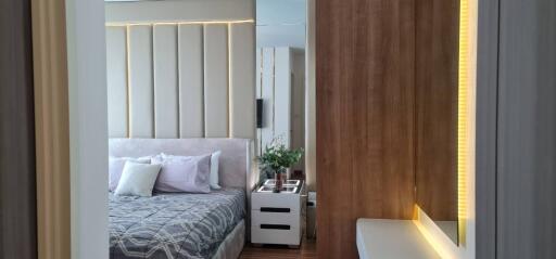 Modern bedroom with stylish decor featuring a bed, bedside table, wooden accent wall, and indoor plants