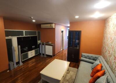 Modern living room with wood flooring, sofa, coffee table, entertainment center, and air conditioning