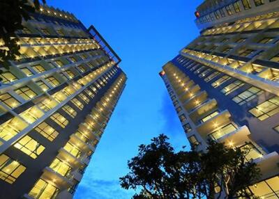 Tall modern apartment buildings with illuminated windows at dusk.