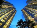 Tall modern apartment buildings with illuminated windows at dusk.