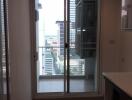 Living area with glass door leading to a balcony offering city views.