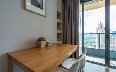 Dining area with a wooden table and chairs next to a large window with a view of the city