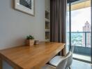 Dining area with a wooden table and chairs next to a large window with a view of the city