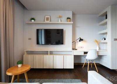 Modern living area with TV, wall-mounted shelves, and desk