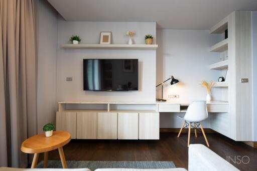 Modern living area with TV, wall-mounted shelves, and desk