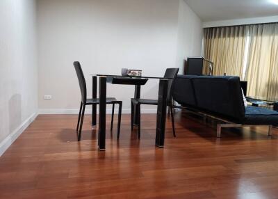 Modern living room with wooden flooring, a dining table, and a sofa