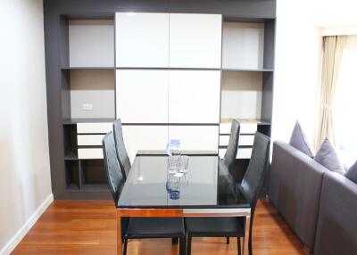 Modern dining area with a glass table and chairs, adjacent to a living room