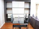 Modern dining area with a glass table and chairs, adjacent to a living room