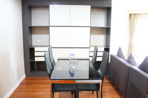 Modern dining area with a glass table and chairs, adjacent to a living room