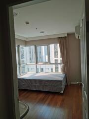 A bedroom with a large window and wooden flooring