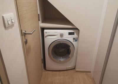 Compact laundry area with washing machine under staircase