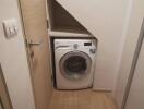 Compact laundry area with washing machine under staircase