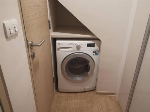 Compact laundry area with washing machine under staircase