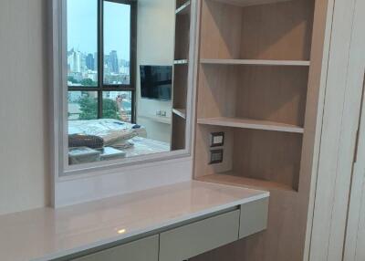 Bedroom with built-in vanity, shelves, large window, city view, and wall-mounted television