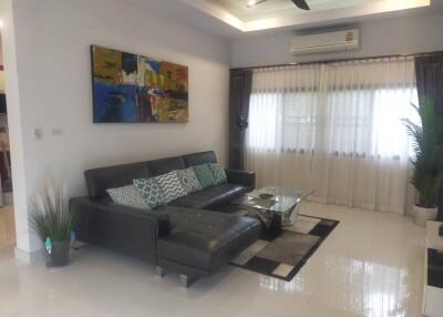 Modern living room with a black sofa, glass coffee table, and wall art